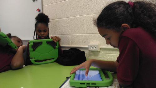 Young students building their Elementari projects together on tablets